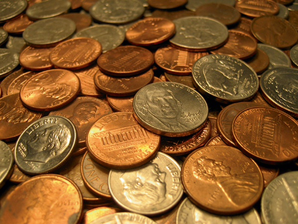 A close-up shot captures a diverse assortment of US coins, including copper pennies, silver dimes, and quarters, creating a textured pile of everyday currency.